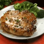 Juicy and perfectly seared brown sugar pork chops garnished with fresh herbs on a white plate.