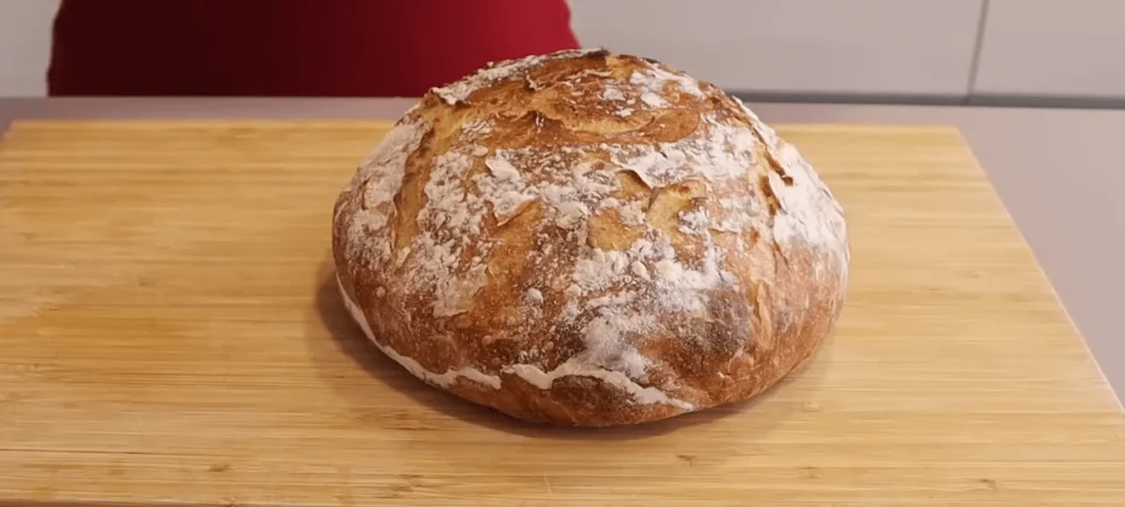 Freshly baked no-knead bread without a Dutch oven on a rustic kitchen countertop.