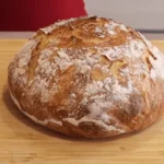 Freshly baked no-knead bread without a Dutch oven on a rustic kitchen countertop.