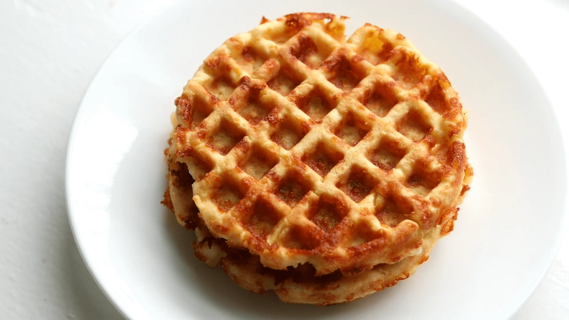 A close-up view of golden, crispy chaffles stacked on a plate, perfect for a low-carb meal or snack.