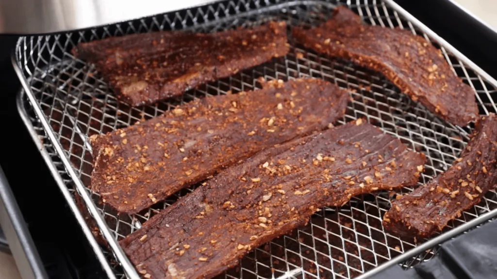 Homemade air fryer beef jerky on a plate, showcasing crispy and flavorful strips of jerky